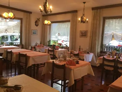 a dining room with tables and chairs and chandeliers at Hotel Nevada in Campitello di Fassa