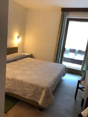 a bedroom with a bed and a large window at Hotel Nevada in Campitello di Fassa