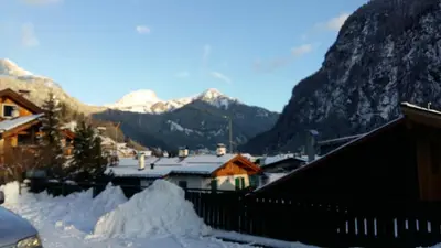 a village covered in snow with mountains in the background at Hotel Nevada in Campitello di Fassa
