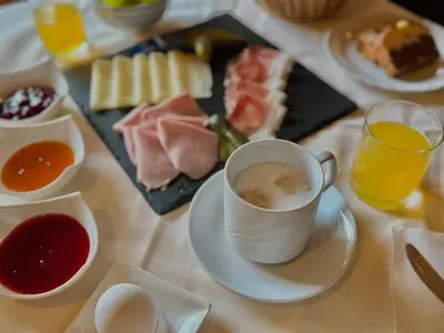 a table with a cup of coffee and a plate of food at Pension Wirt am Bach in Terento