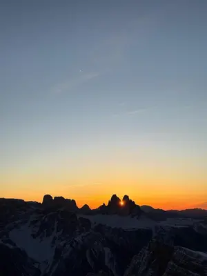 a sunset over the mountains with the sun setting at Pension Wirt am Bach in Terento