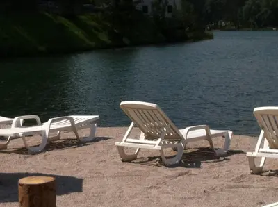 three lounge chairs sitting on the beach near the water at Casa Vacanze Villa Elena in Alleghe