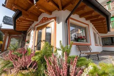 a bench sitting in front of a building with flowers at Hotel Primula in Campitello di Fassa