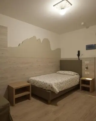 a bedroom with a bed and two end tables at Cesa Rotic in Canazei