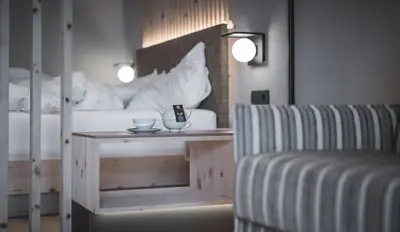 a bedroom with a bed and a table with a chair at Kronplatz-Resort Berghotel Zirm in Valdaora