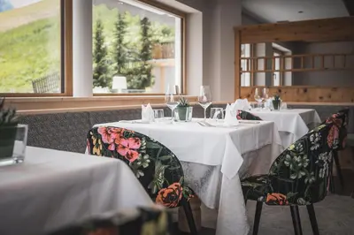 a dining room with two tables with white tablecloths at Kronplatz-Resort Berghotel Zirm in Valdaora