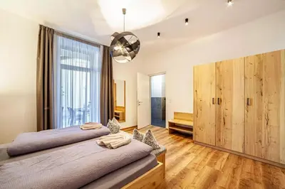 a bedroom with two beds and a large window at Appartements König in Merano