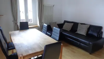 a living room with a black couch and a wooden table at Appartamento Lidia Astor in Alleghe
