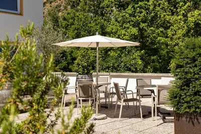a table and chairs with an umbrella on a patio at Landhaus am Gries in Lana