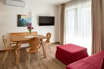 a room with a wooden table and chairs and a bedroom at Landhaus am Gries in Lana