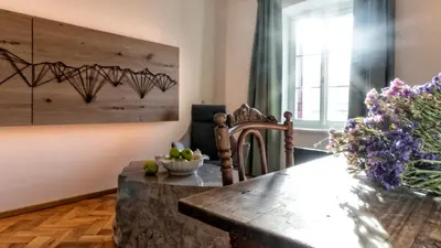 a dining room with a wooden table and flowers at Niedermairhof in Brunico