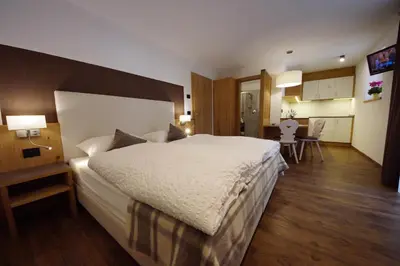 a bedroom with a large bed and a dining room at Chalet Apartments Ambria in La Villa