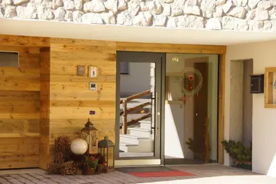 a building with a wooden wall with a staircase at Chalet Apartments Ambria in La Villa