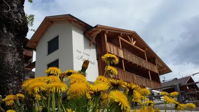 a building with yellow flowers in front of it at Chalet Apartments Ambria in La Villa