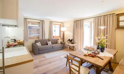 a kitchen and living room with a table and a couch at Chalet Da Mont in Selva di Val Gardena