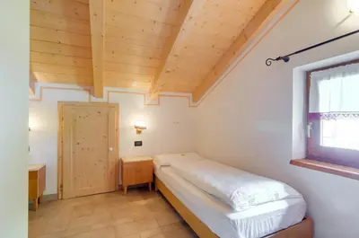 a bedroom with a bed and a wooden ceiling at Roe Apartment in Panchia