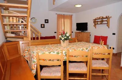 a dining room with a table with chairs and a television at Roe Apartment in Panchia