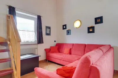 a living room with a red couch and a window at Roe Apartment in Panchia