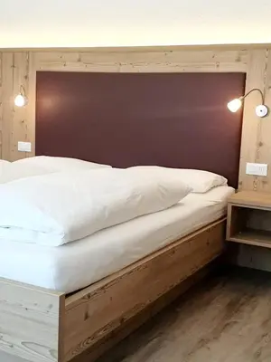 a bedroom with a large bed with a wooden headboard at Residence Majarai in Colfosco