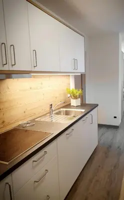 a kitchen with white cabinets and a sink at Residence Majarai in Colfosco