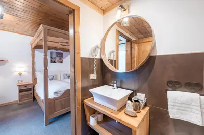 a bedroom with two beds and a desk and a television at Albergo Majorka in Canazei