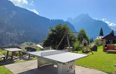 two lounge chairs and an umbrella in the grass at Albergo Majorka in Canazei