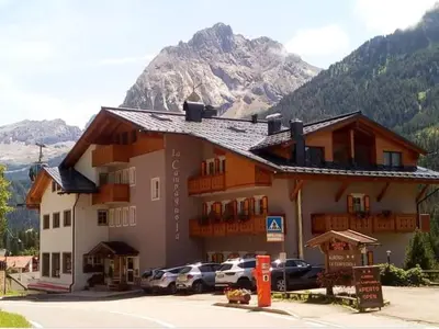 a large building with cars parked in front of it at La Campagnola in Canazei