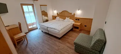 a bedroom with a white bed and a table at La Campagnola in Canazei