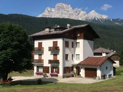 a large white building with a mountain in the background at Appartamento Sole in Borca di Cadore