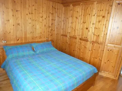 a bedroom with wooden walls and a blue bed at Appartamento Sole in Borca di Cadore