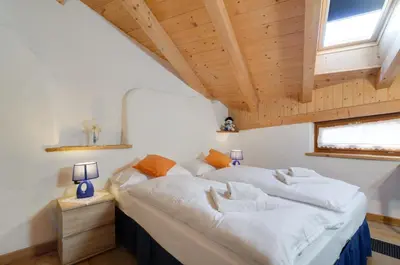 a bedroom with a large bed with white sheets at Tirso Apartament in Castello di Fiemme