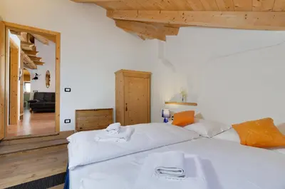 a bedroom with two beds and a living room at Tirso Apartament in Castello di Fiemme