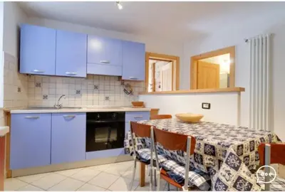 a kitchen with blue cabinets and a table with chairs at Tirso Apartament in Castello di Fiemme