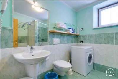a bathroom with a sink and a washing machine at Tirso Apartament in Castello di Fiemme