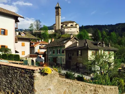 a village with a clock tower and a church at Tirso Apartament in Castello di Fiemme