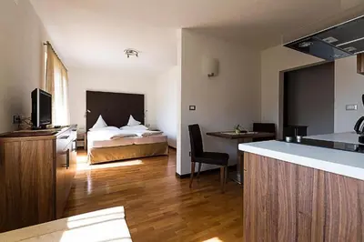 a hotel room with a bed and a kitchen with a counter at Garni Hotel Dorothea in Tirolo