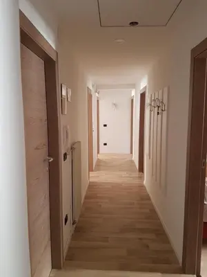 a hallway with white walls and wooden floors at Casa Paola in Pozza di Fassa
