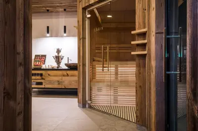 a glass door leading into a bathroom with wooden walls at Garni Larix in Colfosco