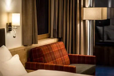 a room with a chair and a lamp and a window at Garni Larix in Colfosco