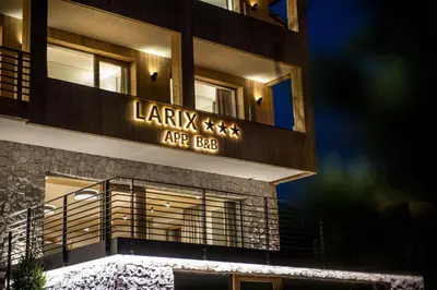 a building with a sign on the side of it at Garni Larix in Colfosco