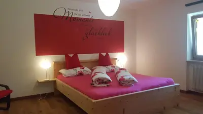 a bedroom with a bed with red sheets and pillows at Partschillerhof in Fiè