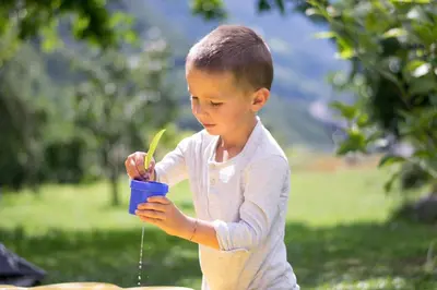 a young boy drinking from a cup with a spoon at Partschillerhof in Fiè
