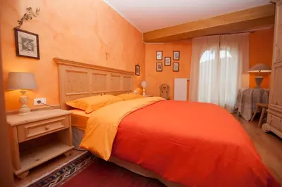 a bedroom with an orange bed and a window at Isarco Suite in Vipiteno