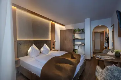 a bedroom with a large bed and a table at Almhotel Lenz in Valdaora
