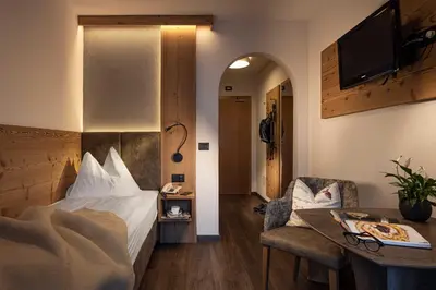 a hotel room with a bed and a table at Almhotel Lenz in Valdaora