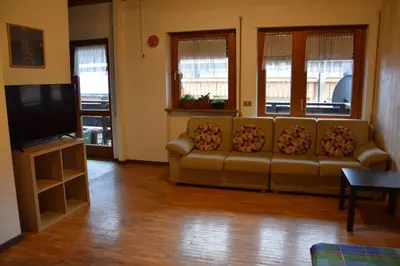 a living room with a couch and a flat screen tv at La Casa Duron in Campitello di Fassa