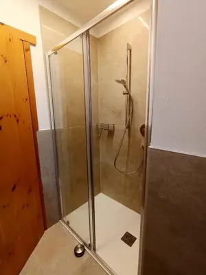 a shower with a glass door in a bathroom at La Casa Duron in Campitello di Fassa