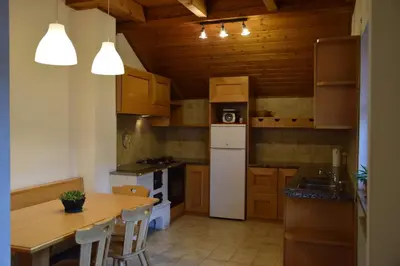 a kitchen with a table and a white refrigerator at La Casa Duron in Campitello di Fassa