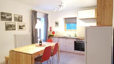 a kitchen with a wooden table and red chairs at Casa Alfredino in Rocca Pietore