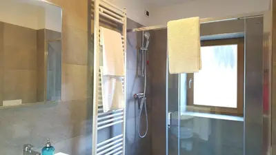 a bathroom with a shower and a sink and a mirror at Casa Alfredino in Rocca Pietore